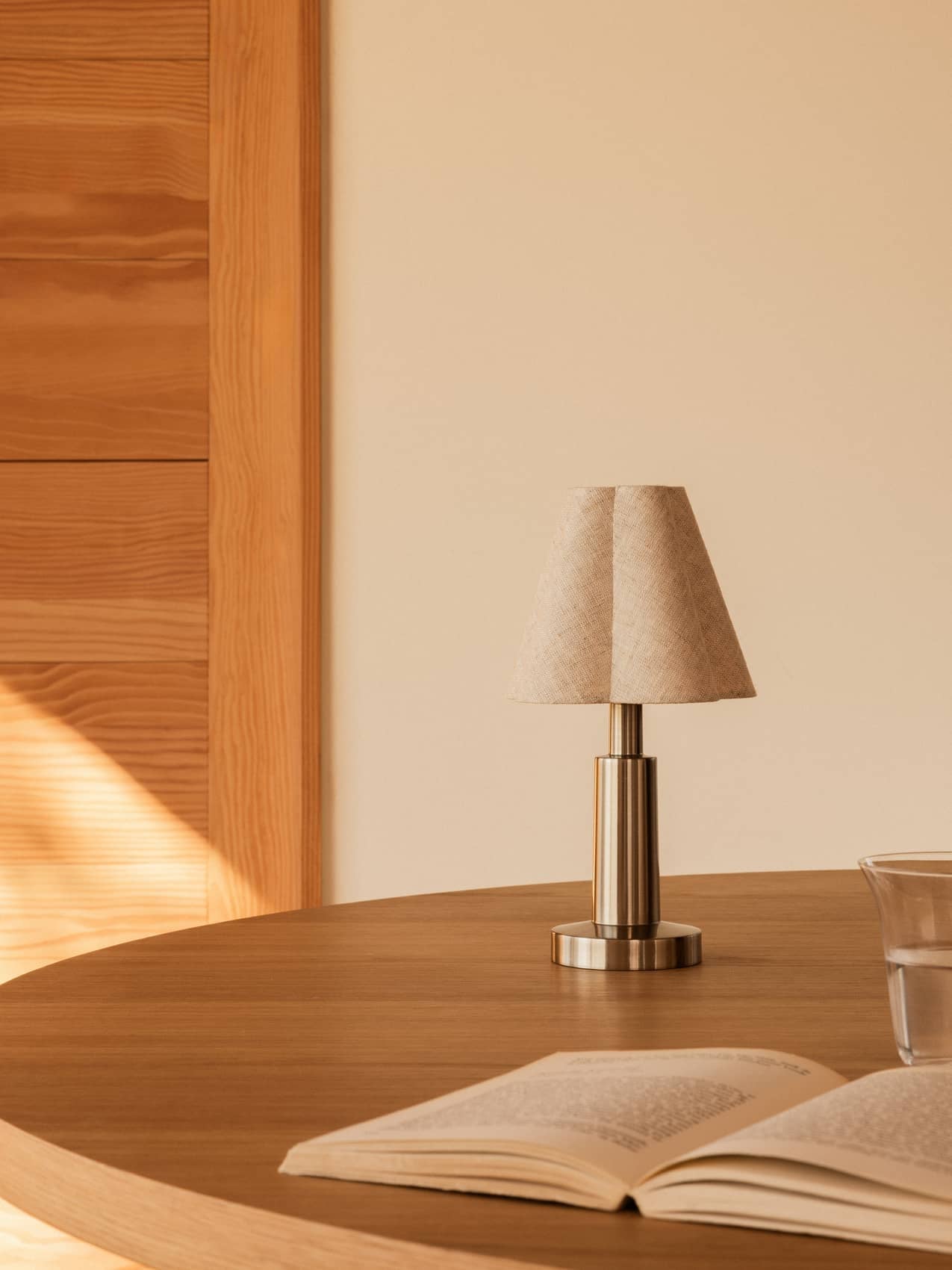 Admiral Portable Lamp by Audo styled on a round timber table with an open book and a glass – In Dubai by WSPR