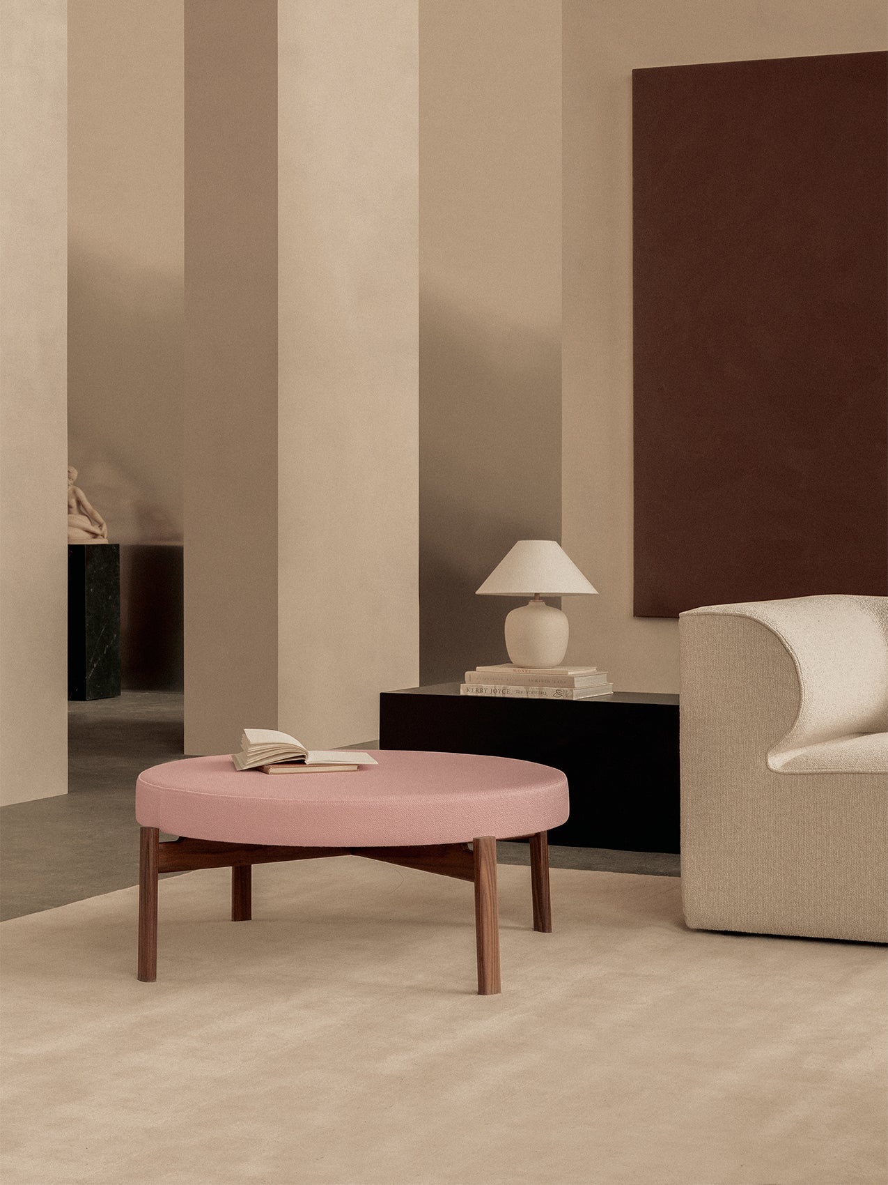Passage Pouf by Audo styled in a warm living room with a pink seat, a table lamp and a curved sofa – In Dubai by WSPR