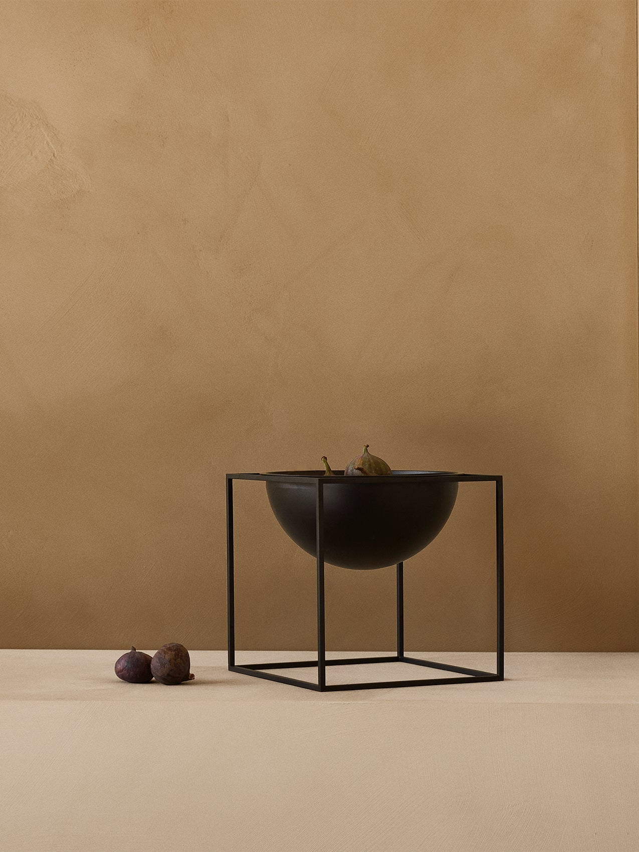 Kubus Bowl by Audo styled on a plinth against a warm plaster wall, with figs – In Dubai by WSPR