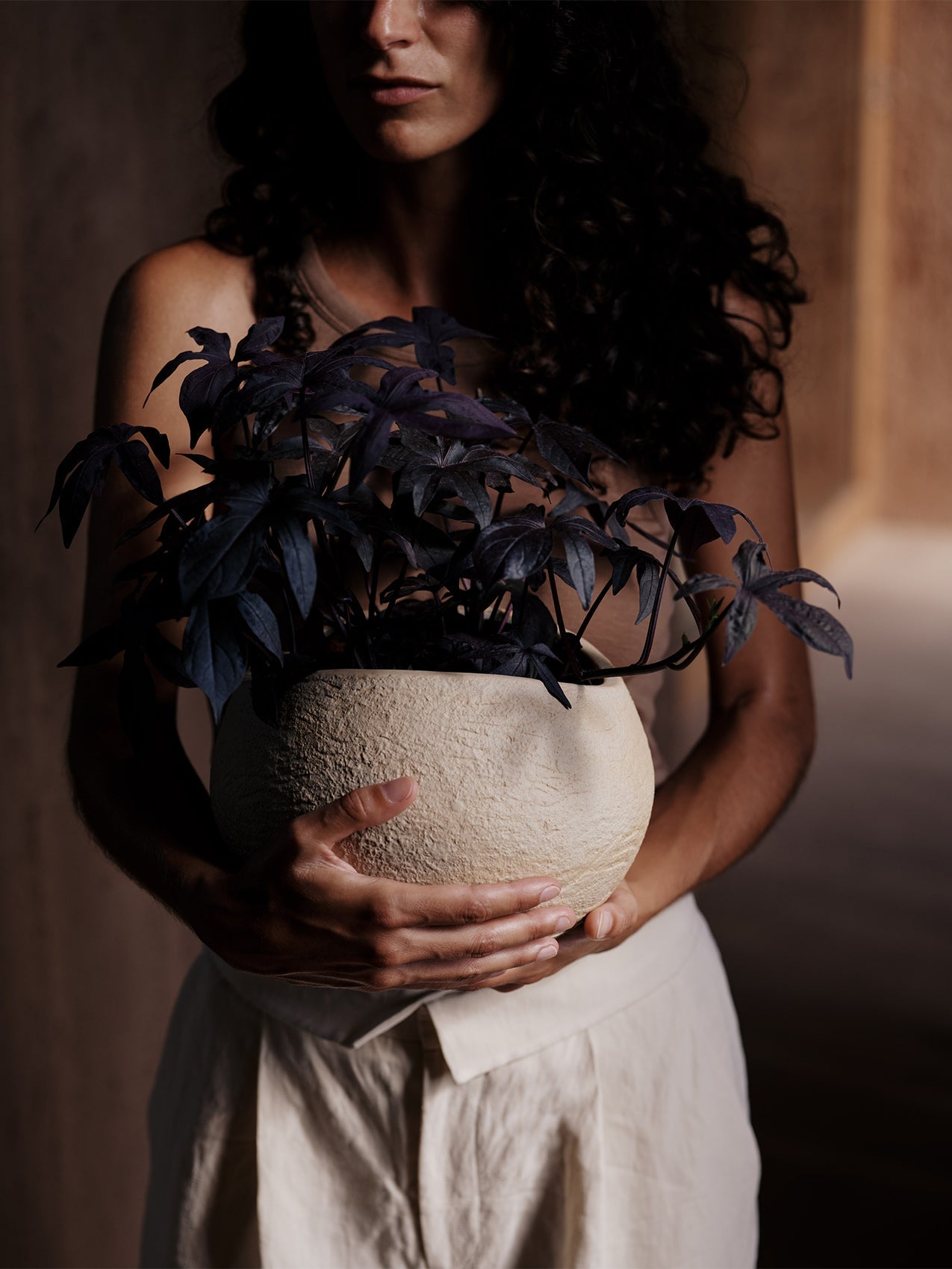 Plantas Planter by Audo styled in a portrait, held with dark leafy stems – In Dubai by WSPR