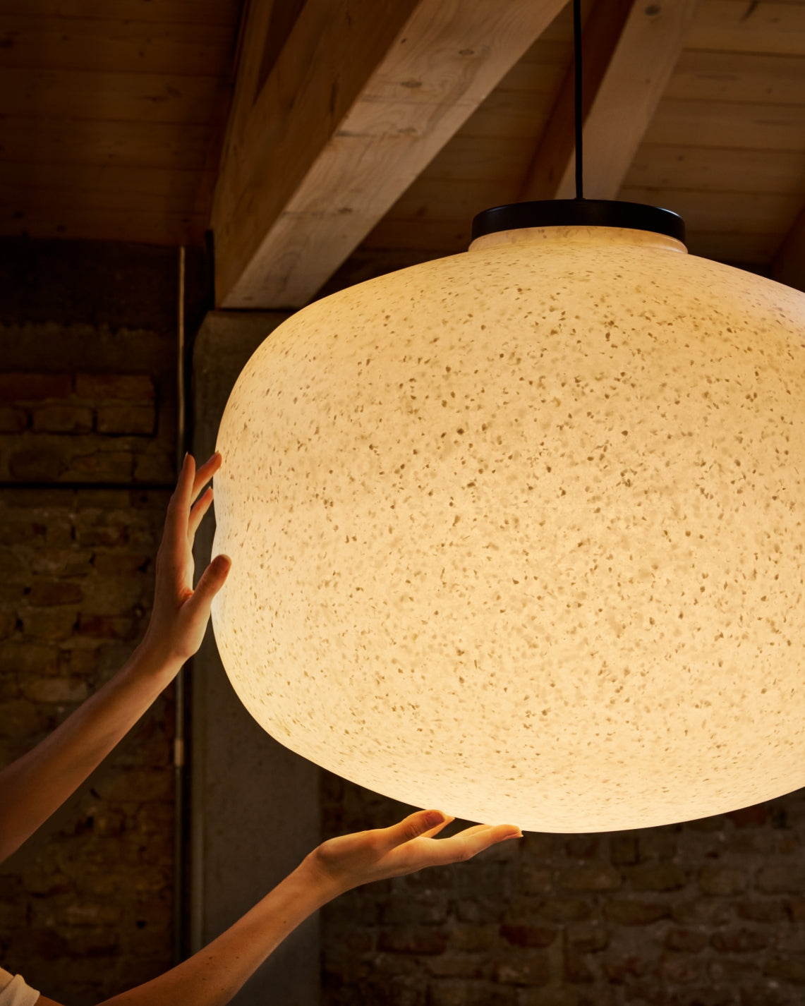Baso Pendant Lamp by Miniforms lit, close view of the White Moon shade held by hands – In Dubai by WSPR