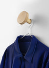 Chiodo Hanger by Miniforms in natural beech, holding a blue jacket on a coat hanger – In Dubai by WSPR