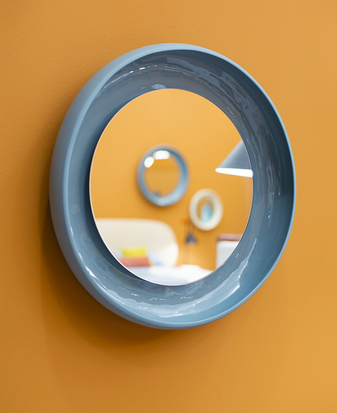 Coque Mirror by Miniforms in blue-grey glazed ceramic, front view on an ochre wall – In Dubai by WSPR