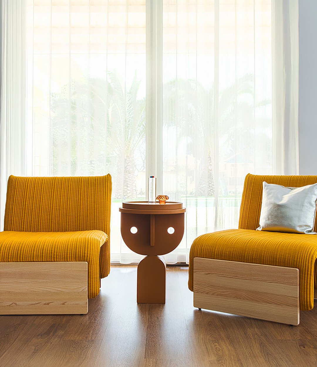 Faces Side Table by Sancal in dark oak between two yellow armchairs – In Dubai by WSPR