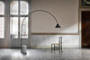 Ozz Floor Lamp by Miniforms in black with a concrete base, arching across a historic room with a chair – In Dubai by WSPR