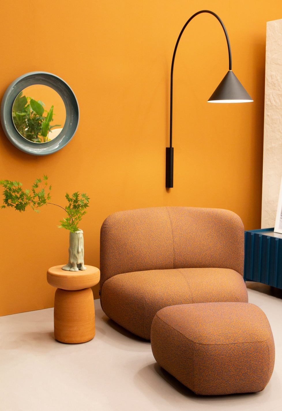 Ozz Wall Lamp by Miniforms in black, styled on an orange wall above a lounge chair – In Dubai by WSPR