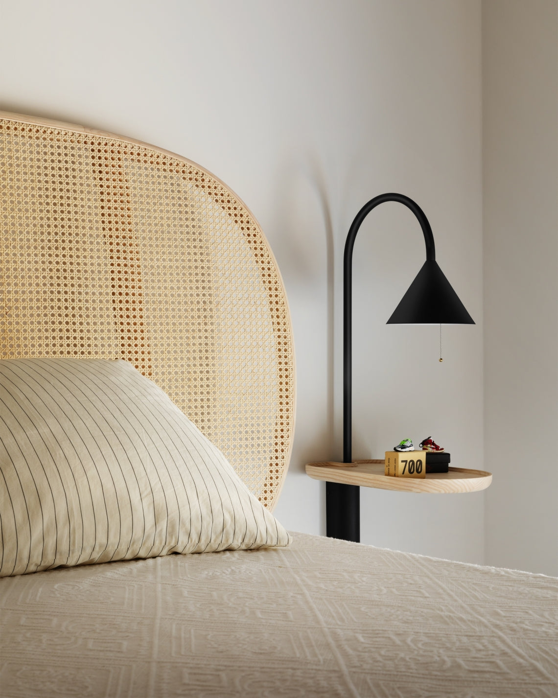 Ozz Wall S Lamp by Miniforms in black metal with an ash shelf, above a bed with a woven cane headboard – In Dubai by WSPR