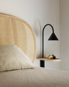 Ozz Wall S Lamp by Miniforms in black metal with an ash shelf, above a bed with a woven cane headboard – In Dubai by WSPR