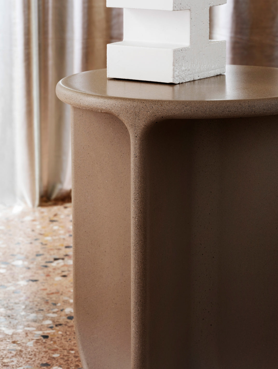 Pinto Coffee Table by Miniforms in a warm brown concrete finish beside a curtain – In Dubai by WSPR