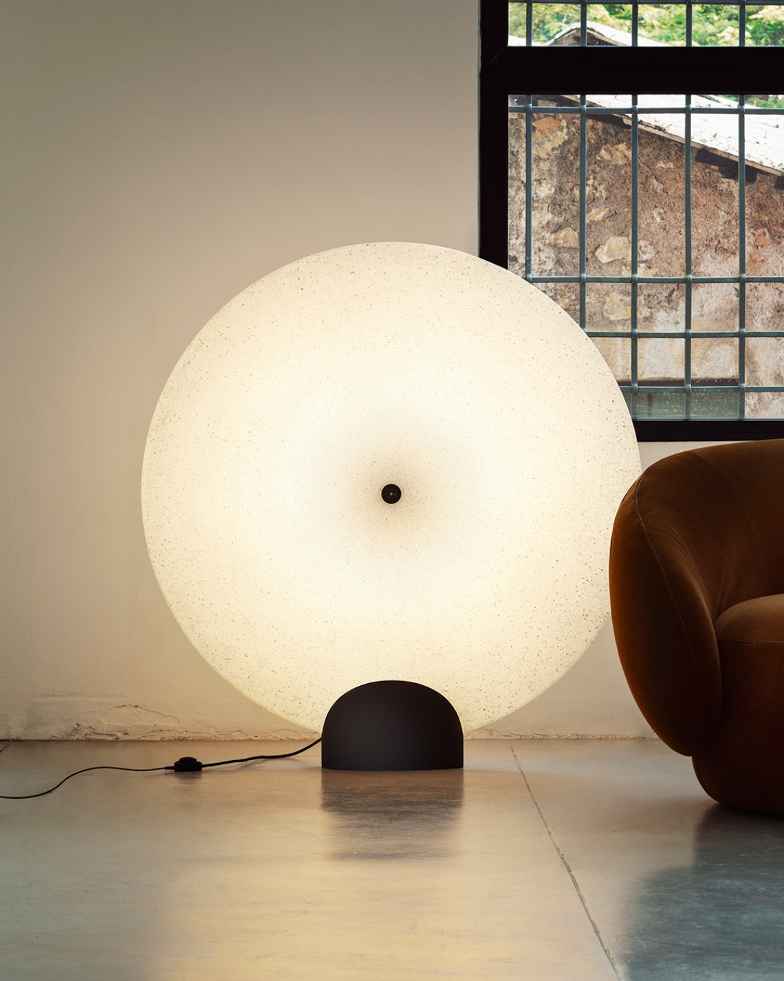 Rificolona 120 Floor Lamp by Miniforms lit beside a brown armchair in a bright industrial room – In Dubai by WSPR