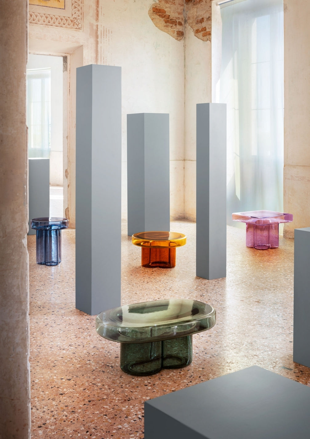 Soda Oval Coffee Table by Miniforms styled in a group of coloured blown glass tables in a hall with grey columns – In Dubai by WSPR